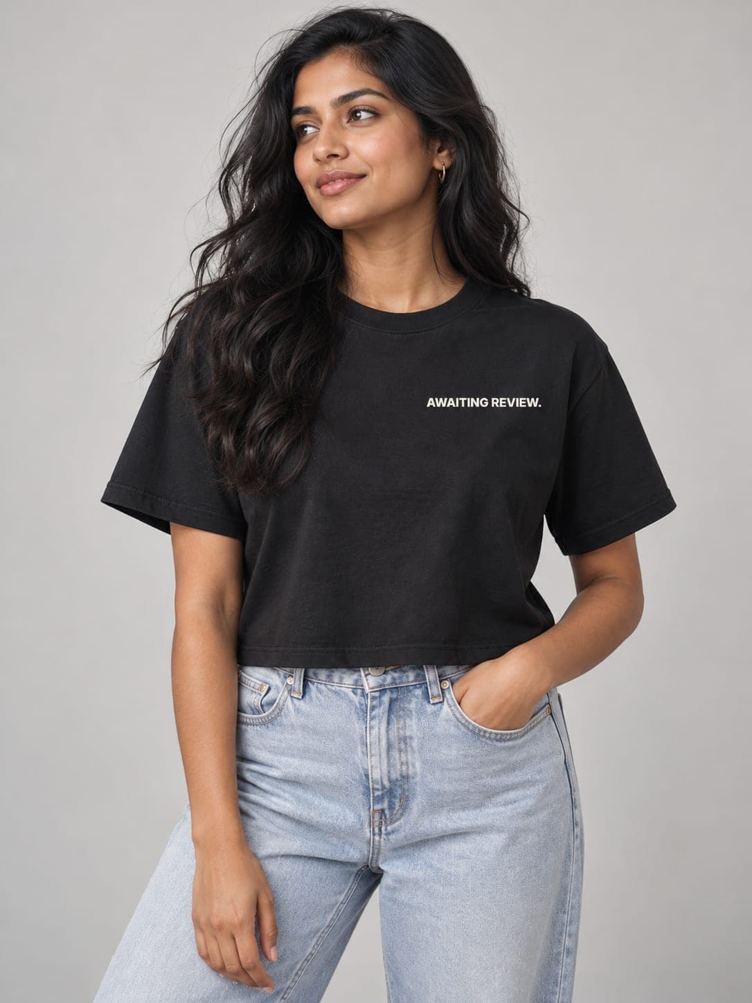 AWAITING REVIEW Crop tee in Black, worn by a model: AWAITING REVIEW. printed left chest. AI-generated mockup.