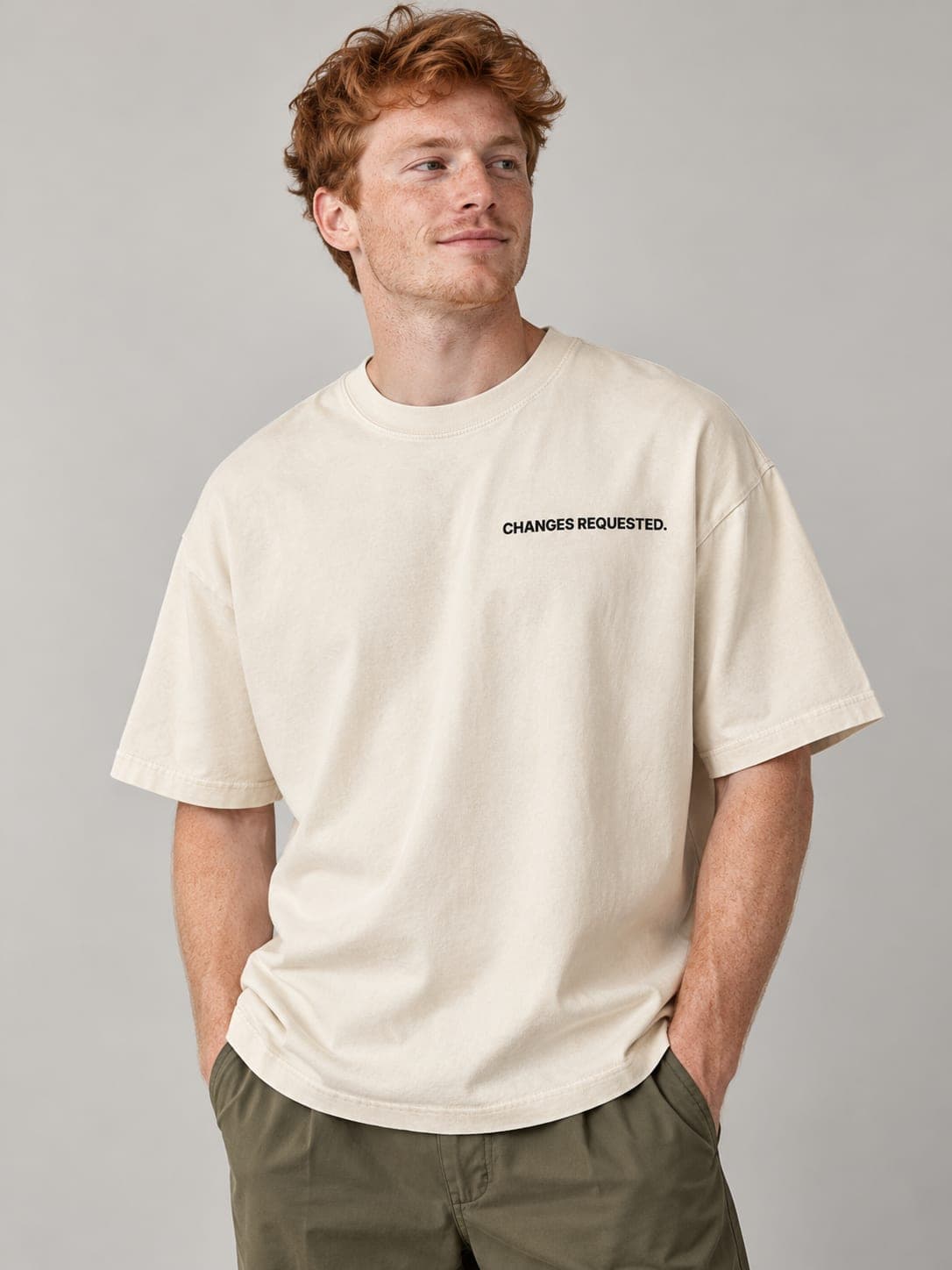 CHANGES REQUESTED Tee in Faded Bone, worn by a model: CHANGES REQUESTED. printed left chest. AI-generated mockup.