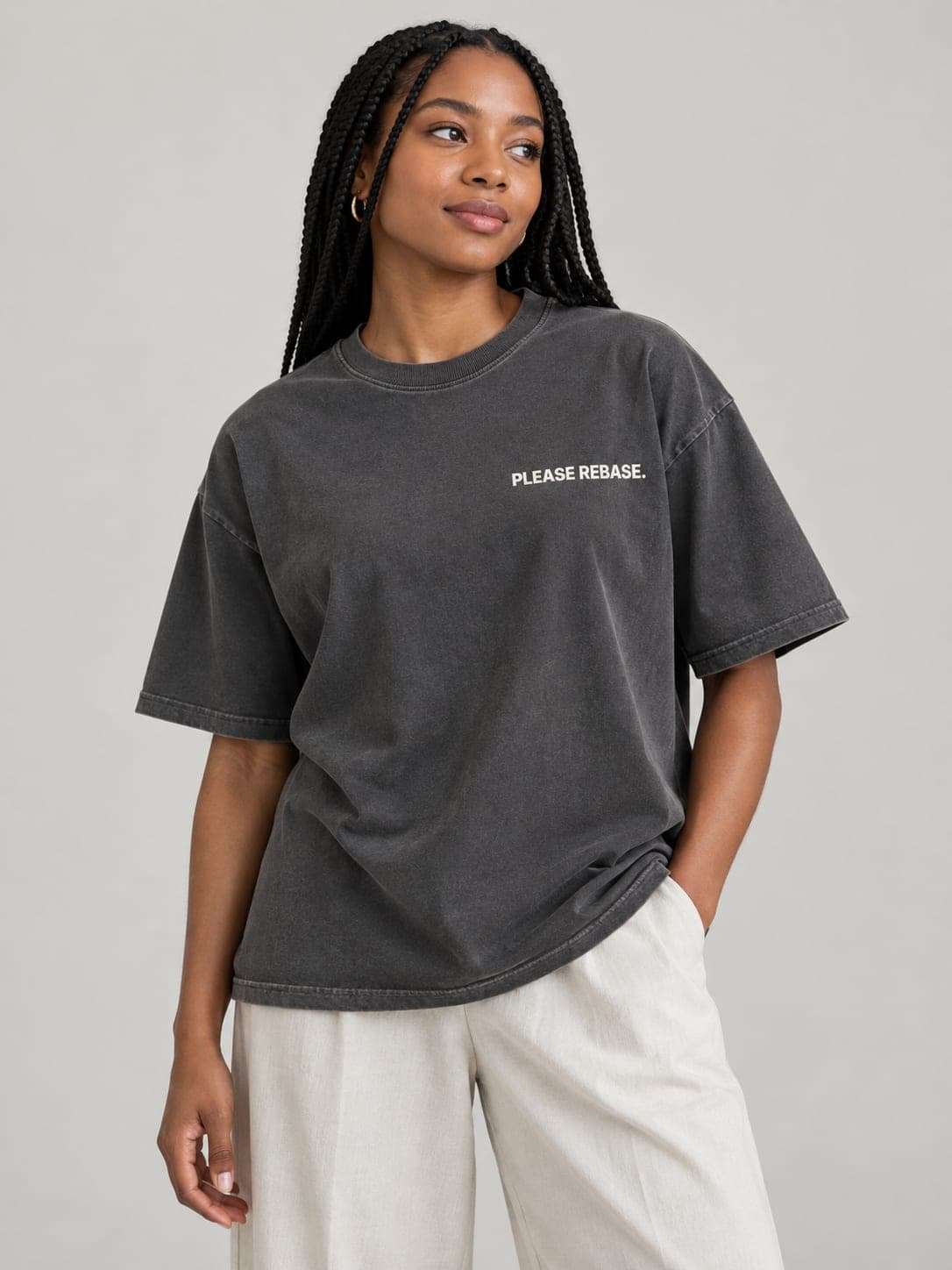 PLEASE REBASE Tee in Faded Coal, worn by a model: PLEASE REBASE. printed left chest. AI-generated mockup.