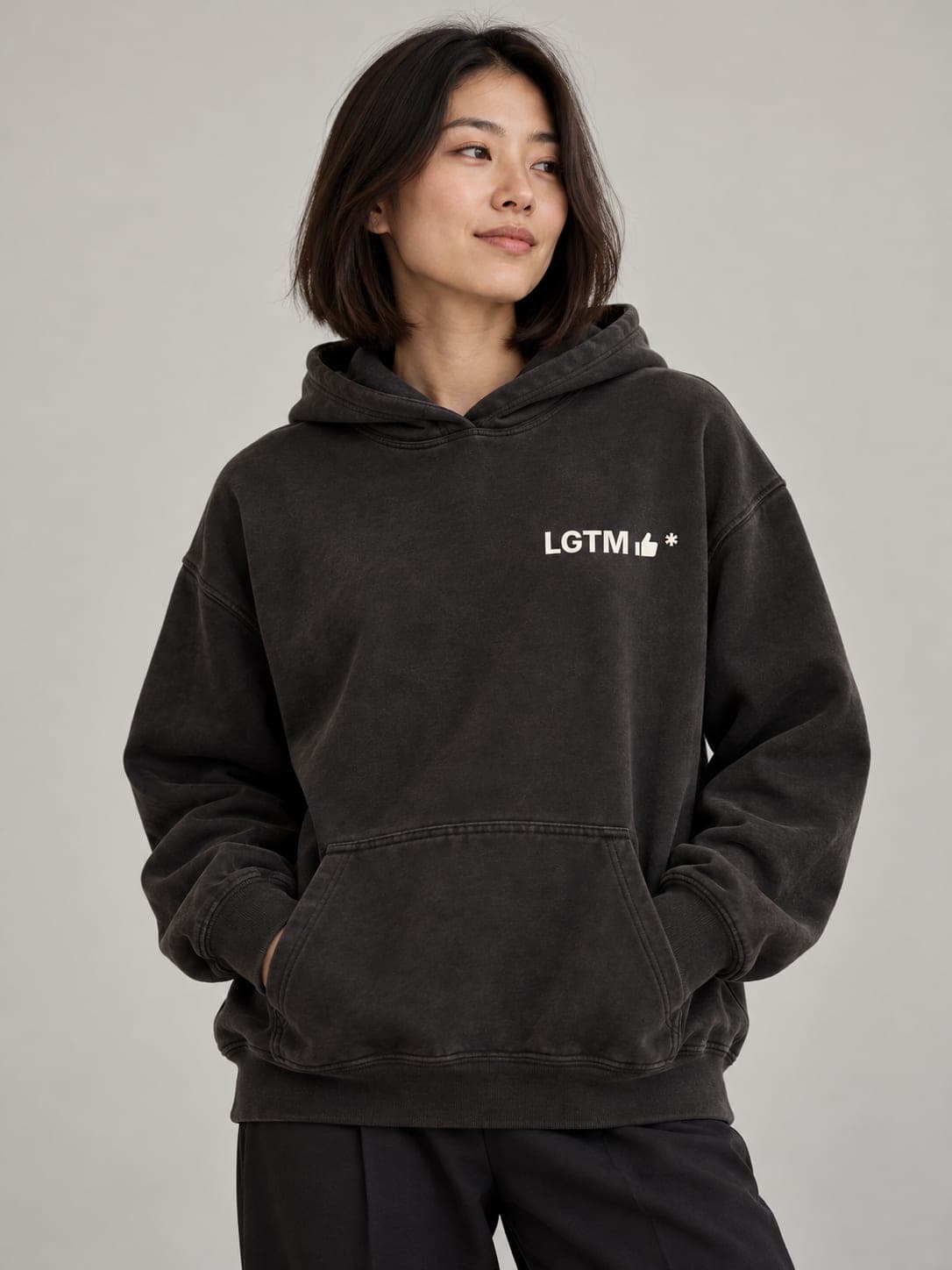 LGTM Hoodie in Pigment Black, worn by a model: LGTM thumbs-up* printed left chest. AI-generated mockup.