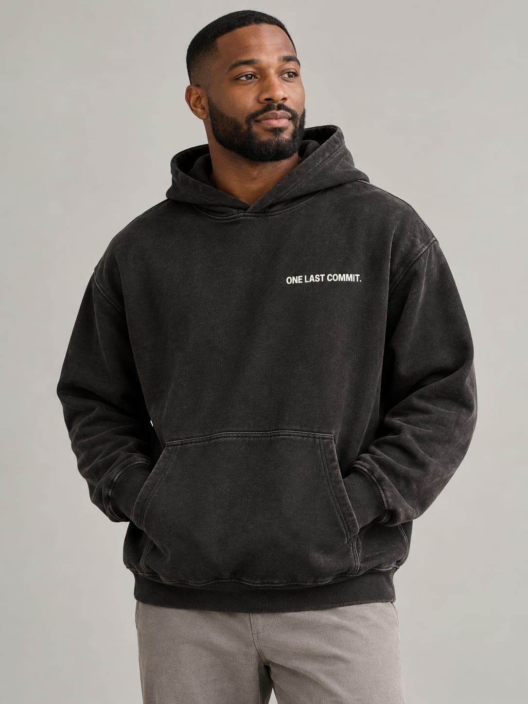 ONE LAST COMMIT Hoodie in Pigment Black, worn by a model: ONE LAST COMMIT. printed left chest. AI-generated mockup.